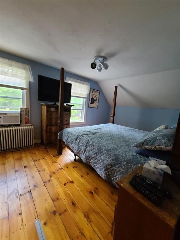 bedroom with lofted ceiling, radiator, and light hardwood / wood-style floors