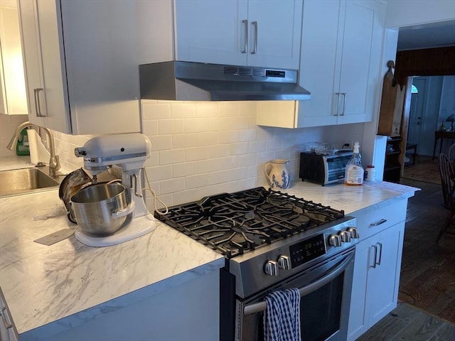 kitchen with dark wood-type flooring, stainless steel gas range, sink, exhaust hood, and white cabinets