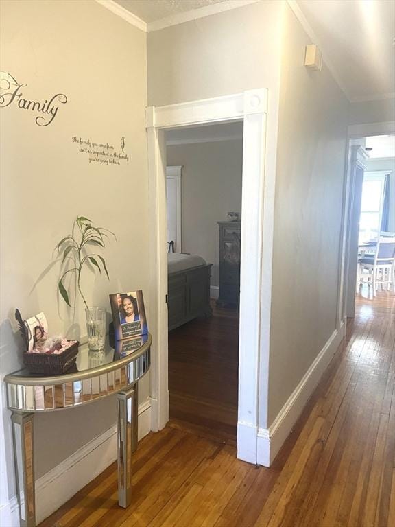 hallway with baseboards, wood finished floors, and crown molding