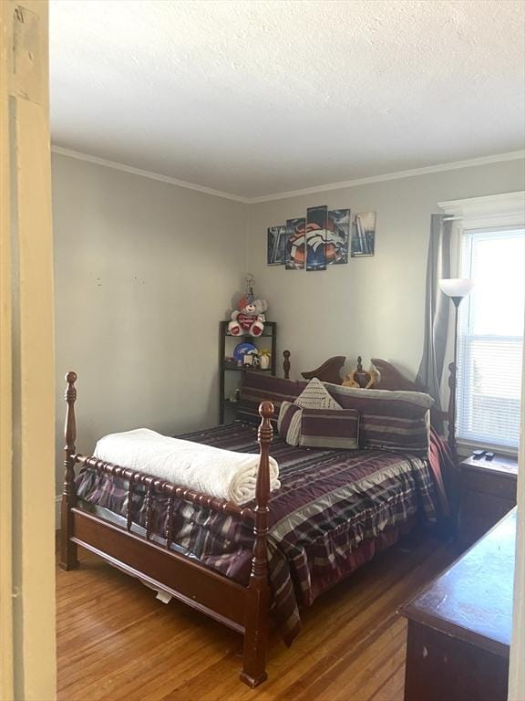 bedroom featuring a textured ceiling, wood finished floors, and crown molding