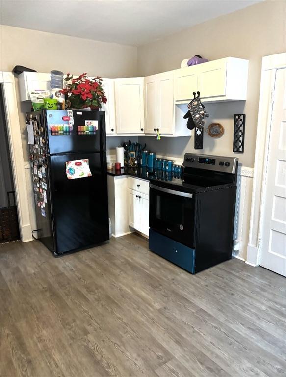 kitchen featuring electric range oven, dark wood-style floors, freestanding refrigerator, and white cabinetry