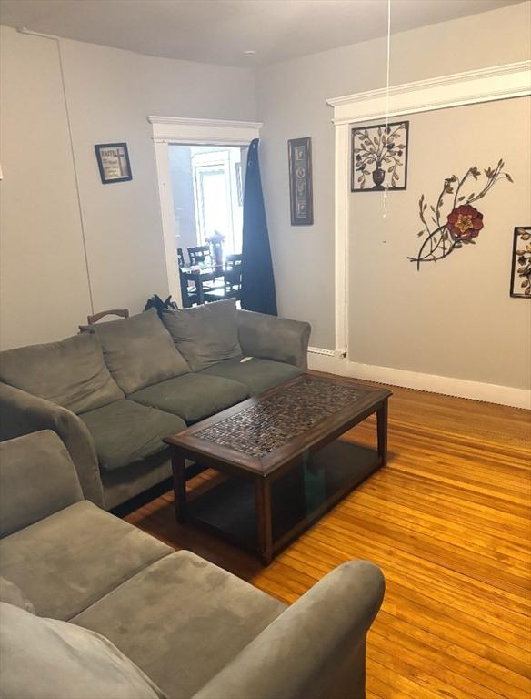 living area with baseboards and wood finished floors