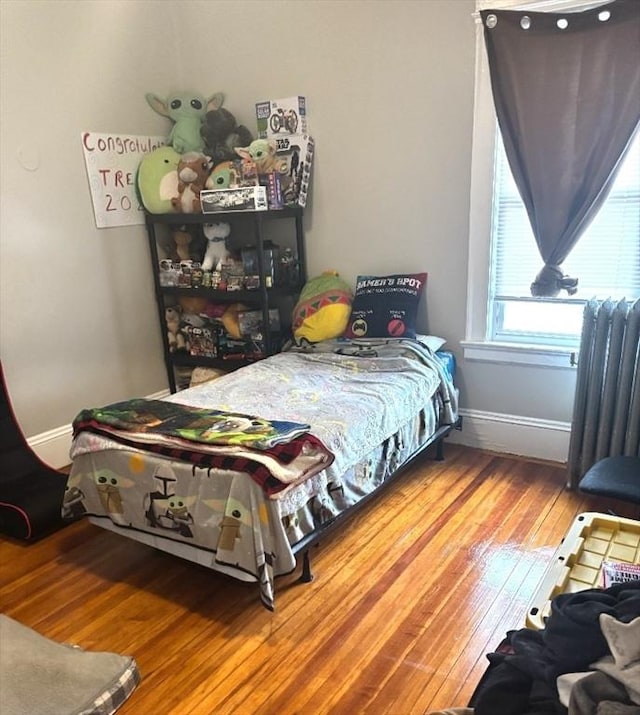 bedroom featuring radiator heating unit, baseboards, and wood finished floors