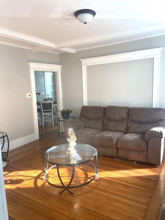 living room featuring crown molding, wood finished floors, and baseboards