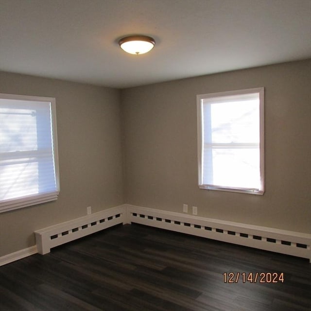 unfurnished room with plenty of natural light, dark wood-type flooring, and a baseboard radiator