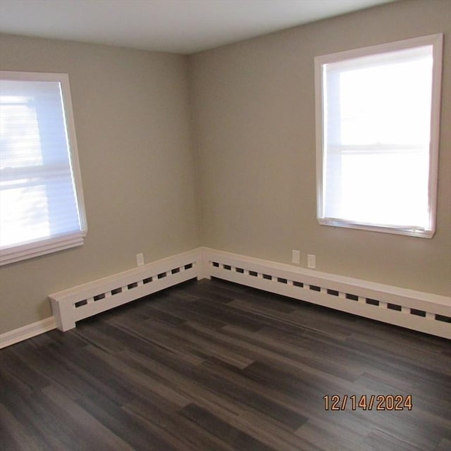 spare room featuring baseboard heating and dark wood-type flooring