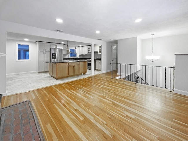 kitchen with a notable chandelier, a center island, pendant lighting, light hardwood / wood-style flooring, and stainless steel fridge with ice dispenser