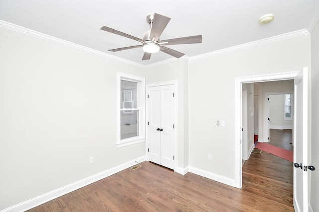 unfurnished bedroom with crown molding, ceiling fan, and dark wood-type flooring