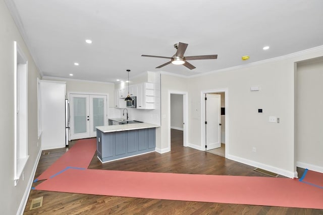 kitchen with hanging light fixtures, dark wood-type flooring, kitchen peninsula, white cabinets, and ornamental molding