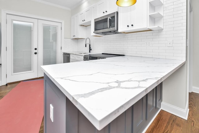 kitchen with white cabinets, appliances with stainless steel finishes, light stone counters, and dark wood-type flooring