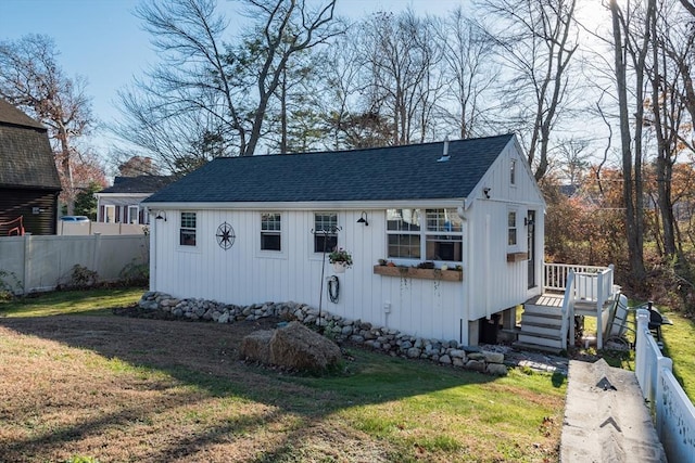 view of front of property featuring a front yard, roof with shingles, and fence