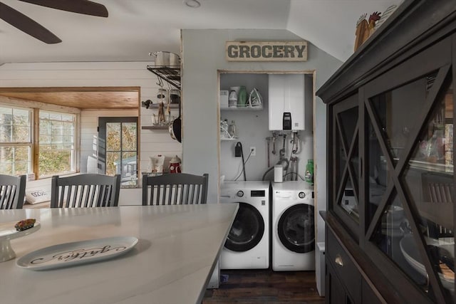 clothes washing area with tankless water heater, wooden walls, laundry area, dark wood-style flooring, and independent washer and dryer