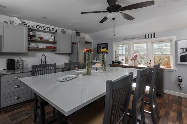 kitchen with open shelves, a breakfast bar area, light stone countertops, and gray cabinetry