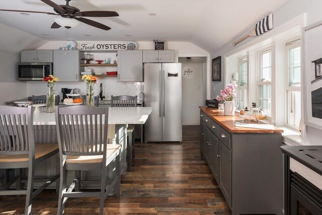 kitchen featuring lofted ceiling, dark wood-style floors, appliances with stainless steel finishes, gray cabinetry, and open shelves