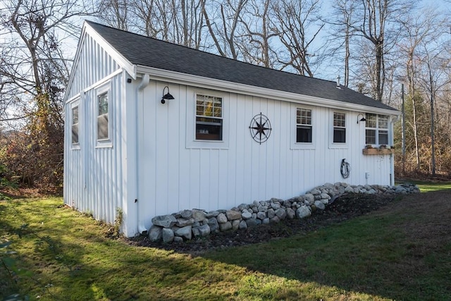 view of side of property featuring roof with shingles and a yard