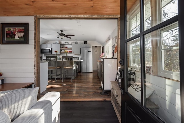 interior space with wood walls, vaulted ceiling, and dark wood-type flooring