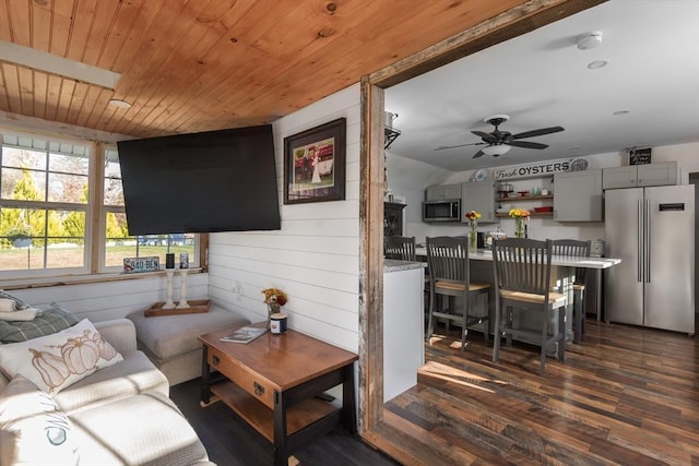 living area with ceiling fan, wood walls, wooden ceiling, and dark wood finished floors