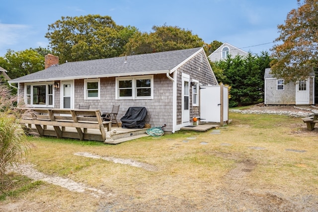 back of house featuring a storage shed, a yard, and a wooden deck