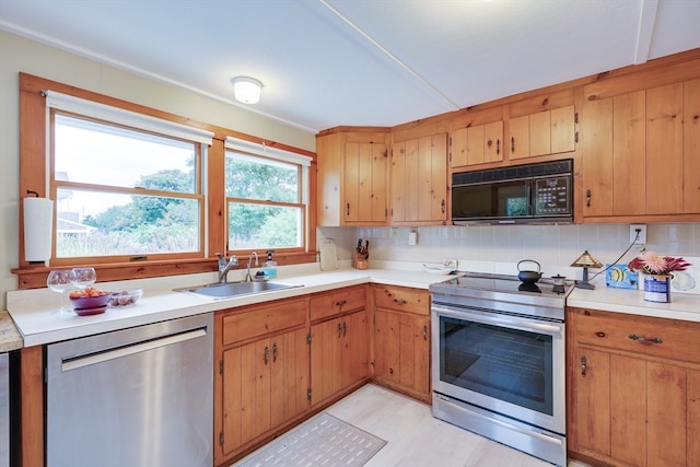 kitchen featuring appliances with stainless steel finishes, sink, light hardwood / wood-style flooring, and decorative backsplash