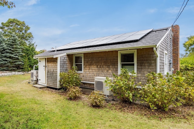 exterior space with central AC unit, a lawn, and solar panels