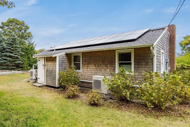 rear view of property with a lawn, solar panels, and central air condition unit