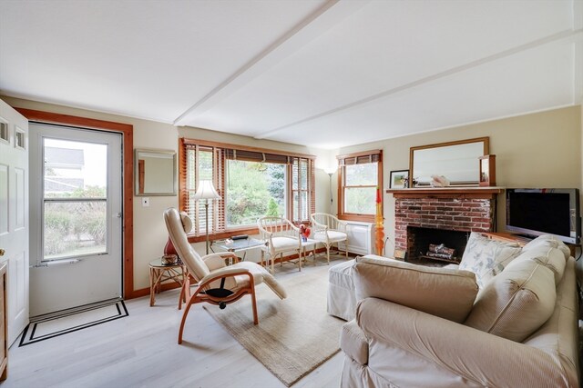 living room with a brick fireplace and light wood-type flooring