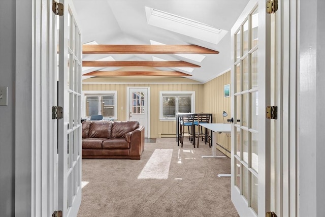 interior space with french doors, lofted ceiling with skylight, wood walls, and light colored carpet