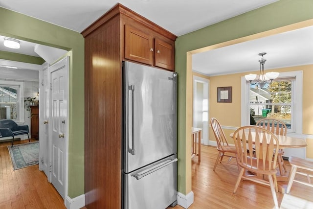 kitchen featuring a notable chandelier, crown molding, light wood-type flooring, decorative light fixtures, and stainless steel fridge