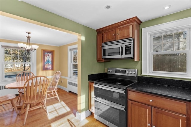 kitchen with hanging light fixtures, radiator, appliances with stainless steel finishes, and a healthy amount of sunlight