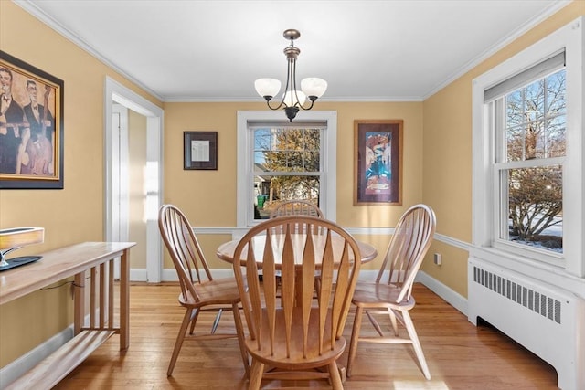 dining space featuring light wood-type flooring, radiator, an inviting chandelier, and crown molding