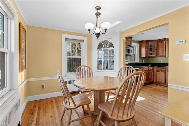 dining room with crown molding, light wood-type flooring, radiator, and a notable chandelier