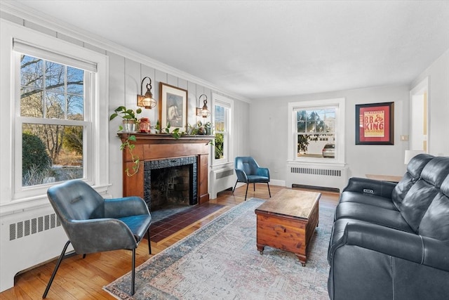 living room featuring hardwood / wood-style flooring, radiator heating unit, and crown molding