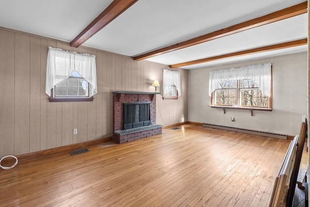 unfurnished living room featuring a brick fireplace, light hardwood / wood-style flooring, a wealth of natural light, beam ceiling, and a baseboard heating unit