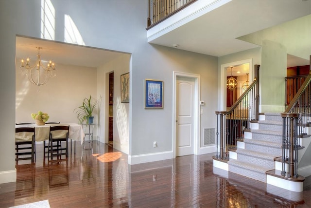 entryway with a high ceiling, dark hardwood / wood-style floors, and a chandelier