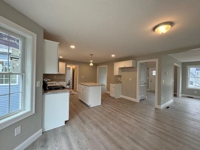 kitchen with a kitchen island, white cabinets, and light wood-style floors