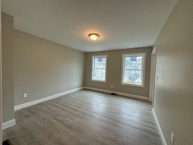 spare room featuring baseboards and wood finished floors