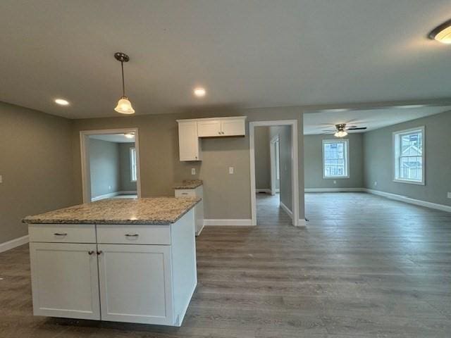 kitchen with a kitchen island, wood finished floors, white cabinetry, and baseboards