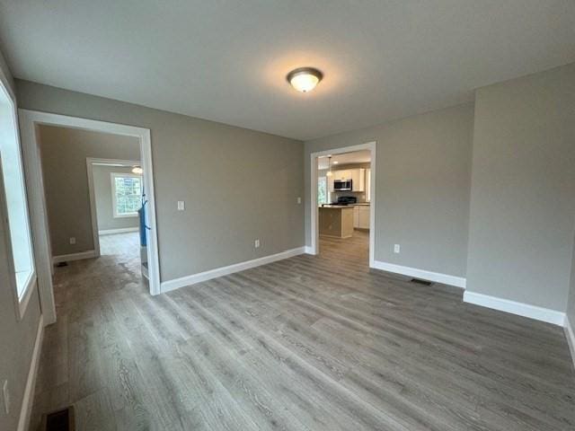 unfurnished room with visible vents, baseboards, and wood finished floors