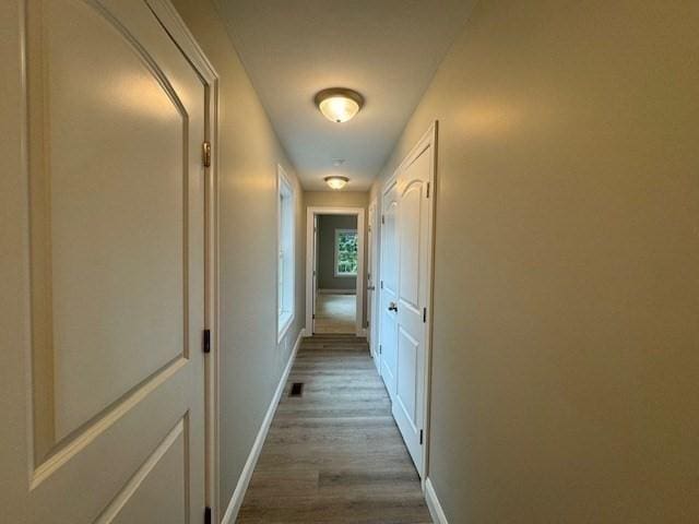 hall featuring visible vents, baseboards, and dark wood-style flooring