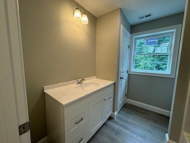 bathroom featuring visible vents, vanity, baseboards, and wood finished floors