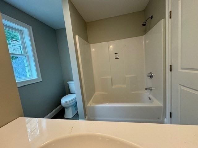 bathroom featuring shower / bathtub combination, toilet, and baseboards