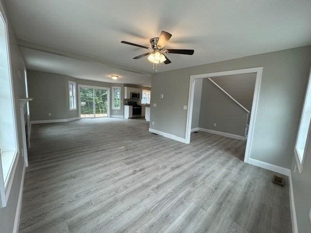 unfurnished living room featuring ceiling fan, baseboards, and wood finished floors