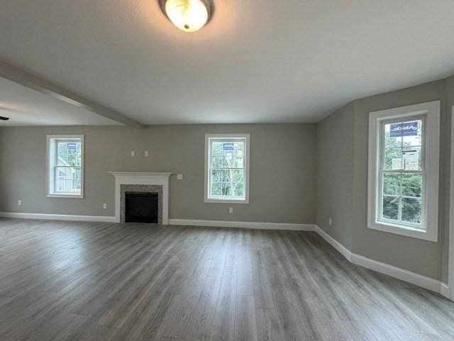 unfurnished living room with a fireplace, baseboards, and wood finished floors