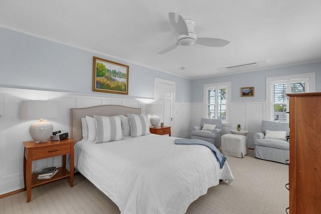 bedroom featuring ornamental molding, carpet, wainscoting, and a ceiling fan