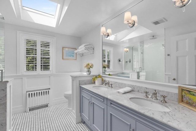 bathroom featuring a skylight, a stall shower, visible vents, radiator, and a sink