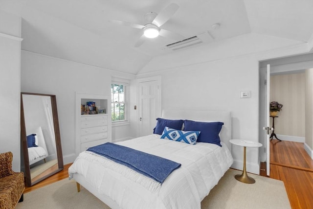 bedroom featuring vaulted ceiling, wood finished floors, a ceiling fan, and baseboards