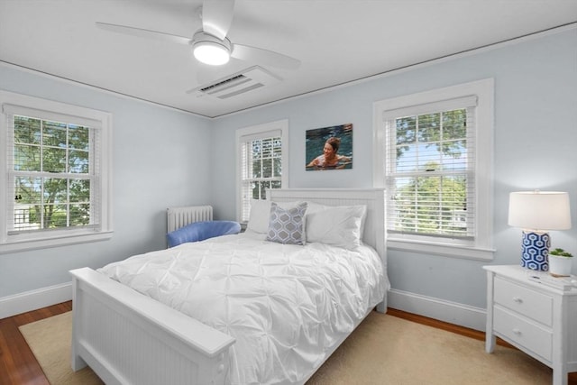 bedroom featuring radiator, baseboards, visible vents, and wood finished floors