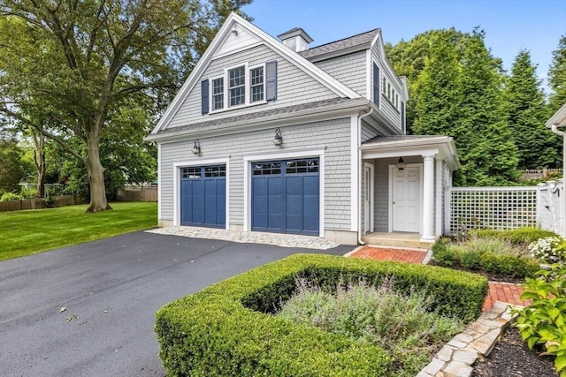 view of front of home featuring a garage, fence, a front lawn, and aphalt driveway