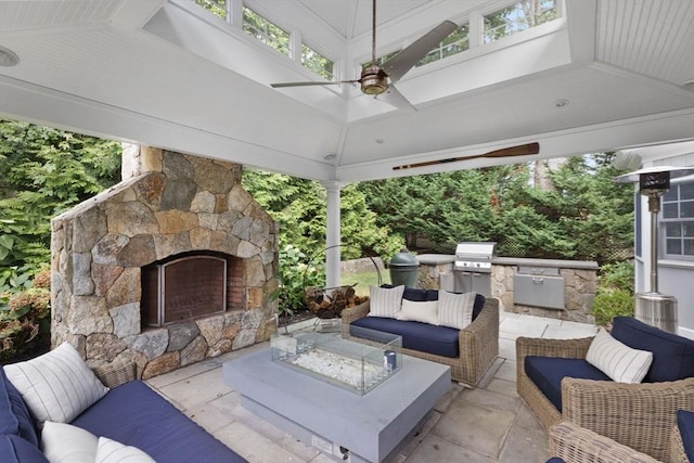 view of patio with a ceiling fan, area for grilling, a grill, a gazebo, and an outdoor living space with a fireplace