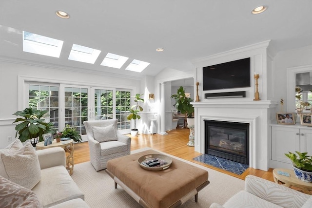 living room featuring light wood-style floors, a fireplace with flush hearth, vaulted ceiling, and recessed lighting